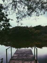 Footbridge over lake against sky