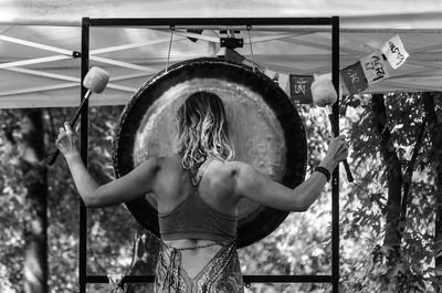 Rear view of woman playing traditional gong