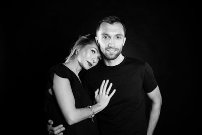 Portrait of confident couple standing against black background