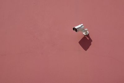 Low angle view of security camera on red wall