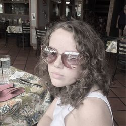 Portrait of young woman drinking glass on table