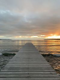 Pier over sea against sky during sunset