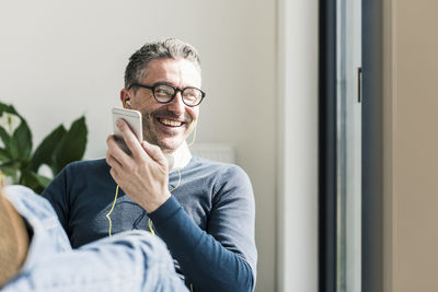 Portrait of smiling businessman using smartphone and earphones