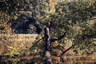 Man standing on fallen tree in lake
