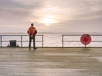 Man tourist in autumn mist on wooden pier above sea. depression dark atmosphere.