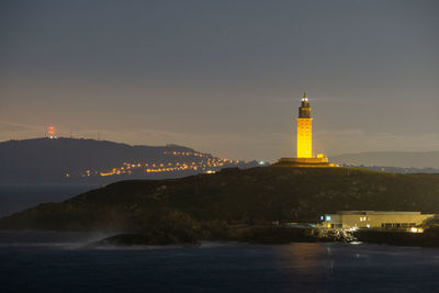 Lighthouse by sea against sky at night