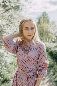 Blonde girl on a spring walk in the garden with cherry blossoms. female portrait, close-up. 