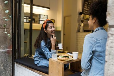 Side view of happy woman sitting at restaurant table