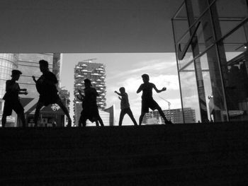 Silhouette boys dancing with buildings in background