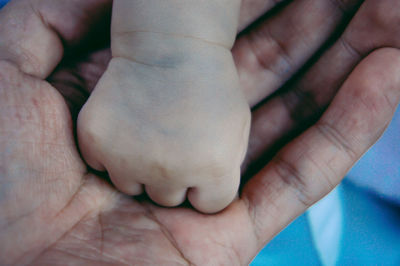 Cropped image of parent holding baby hand