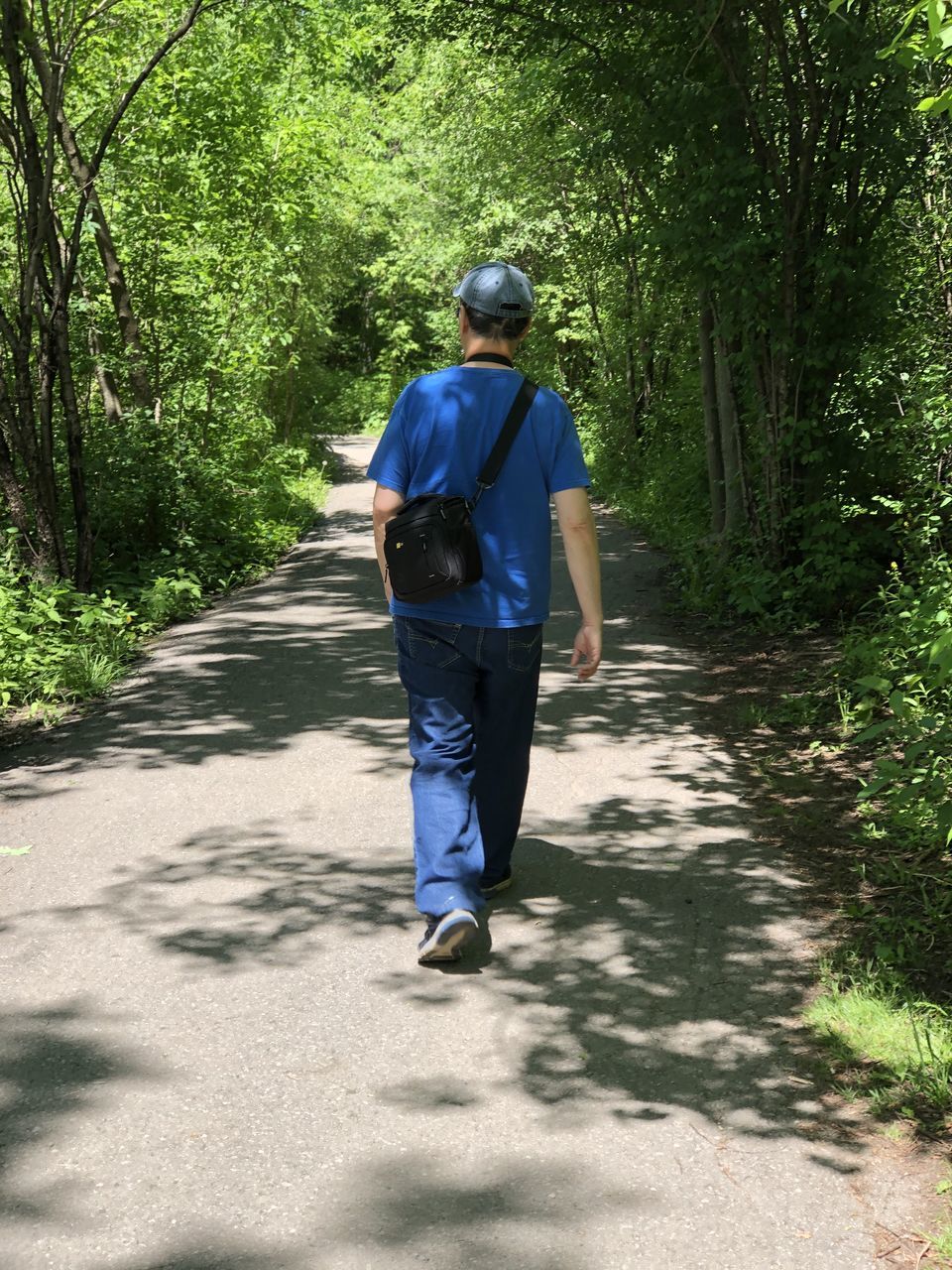 REAR VIEW OF MAN WALKING ON FOOTPATH