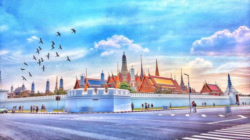 View of birds by building against cloudy sky