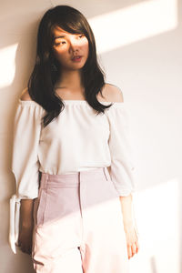 Young woman standing by wall at home