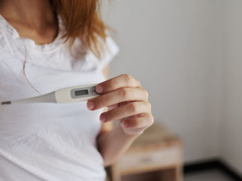 Midsection of woman holding thermometer