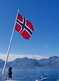 Norwegian flag on mountain against blue sky