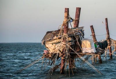 Traditional windmill in sea against clear sky