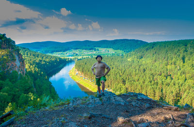 Man standing on mountain against river in forest