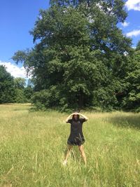 Woman standing on grassy field against trees