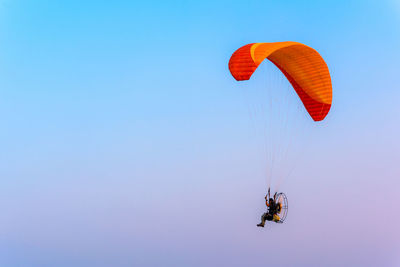 Low angle view of person paragliding against clear blue sky