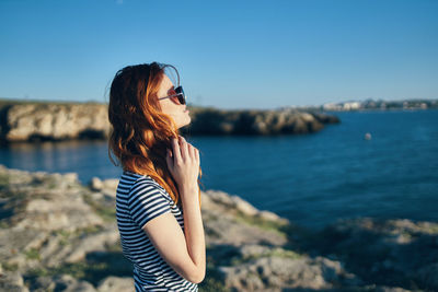 Young woman standing in sea against sky