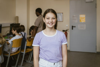 Portrait of smiling girl standing in computer class at school