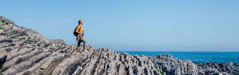 Woman with backpack walking through flysch rock landscape