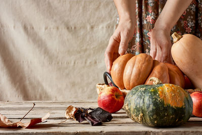 Midsection of man holding pumpkin on table