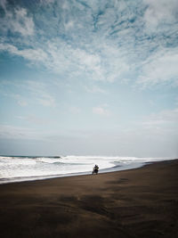 Man riding motorcycle on beach against sky