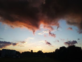 Silhouette trees against dramatic sky during sunset