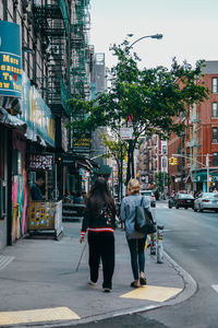 Rear view of people walking on sidewalk