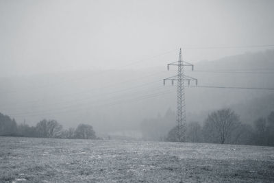 Electricity pylon on field against sky