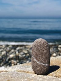 Close-up of pebbles on rock at beach against sky