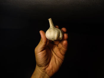 Close-up of hand holding bread against black background