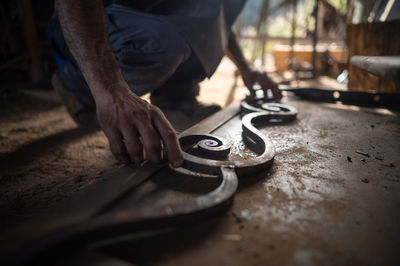 Close up of a blacksmith's hands checking the measurements of a grating in his workshop. 