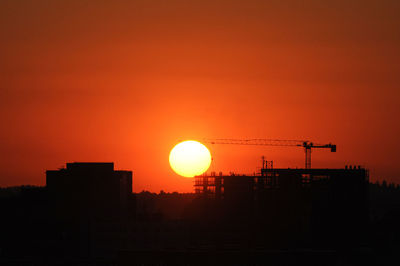 Silhouette cranes against sky during sunset