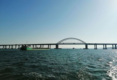 Bridge over black sea against clear sky