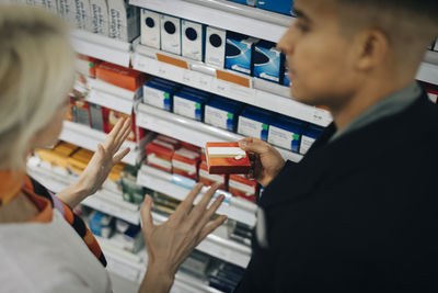 High angle view of female pharmacist explaining medicine to male customer at store