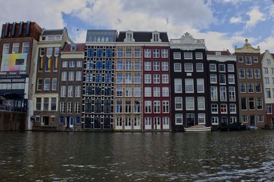 Buildings by river against sky