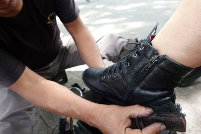 Midsection of man polishing shoe of customer