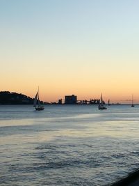 Silhouette boats in calm sea at sunset