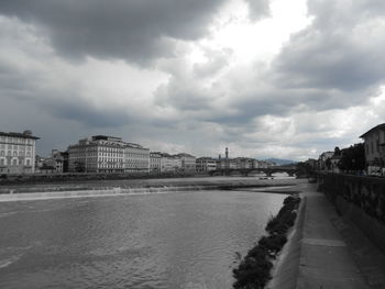 Bridge over river by buildings in city against sky