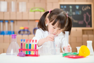 Cute girl holding toy while sitting on table