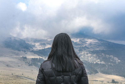 Rear view of woman standing on mountain against sky