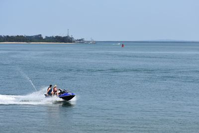 Men on boat in sea against clear sky