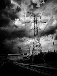 Low angle view of electricity pylon against dramatic sky