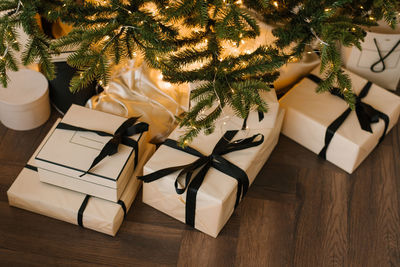 Expensive christmas gifts are lying under the christmas tree with lights, top view