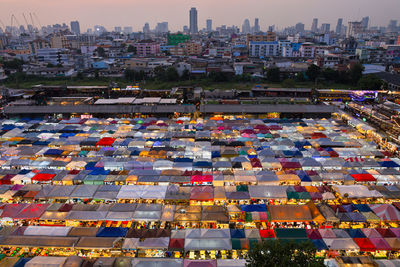 Illuminated market against cityscape during sunset