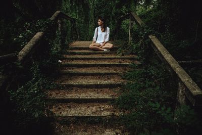 Young woman sitting on steps in forest