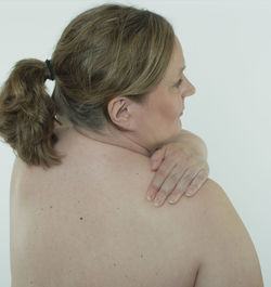 Rear view of shirtless young woman against white background