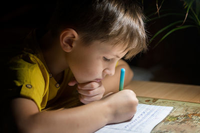 Close-up of boy drawing on book at home